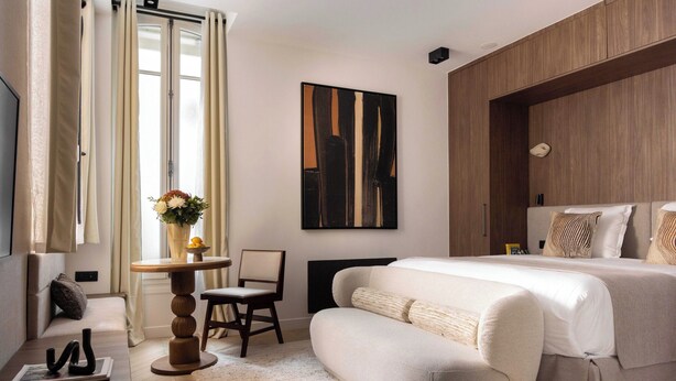 A modern bedroom with a large bed, a sofa, a small table with a vase, and a painting on the wall. - Luxury 2P Studio - Monceau / Paris 8th (Paris)