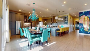 Une cuisine moderne avec un îlot central, des chaises de couleur turquoise et un lustre.
