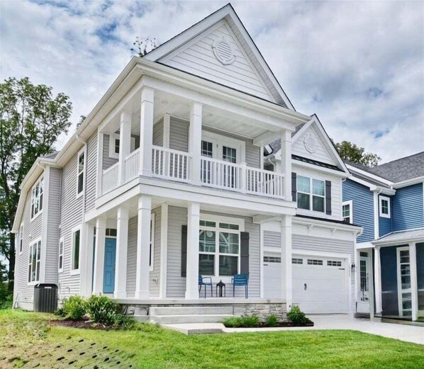 A two-story house with a front porch, a garage, and a small garden area. - Rehoboth Beach Vacation Rentals: Luxury House at Arbor Lyn w Ent (Rehoboth Beach)