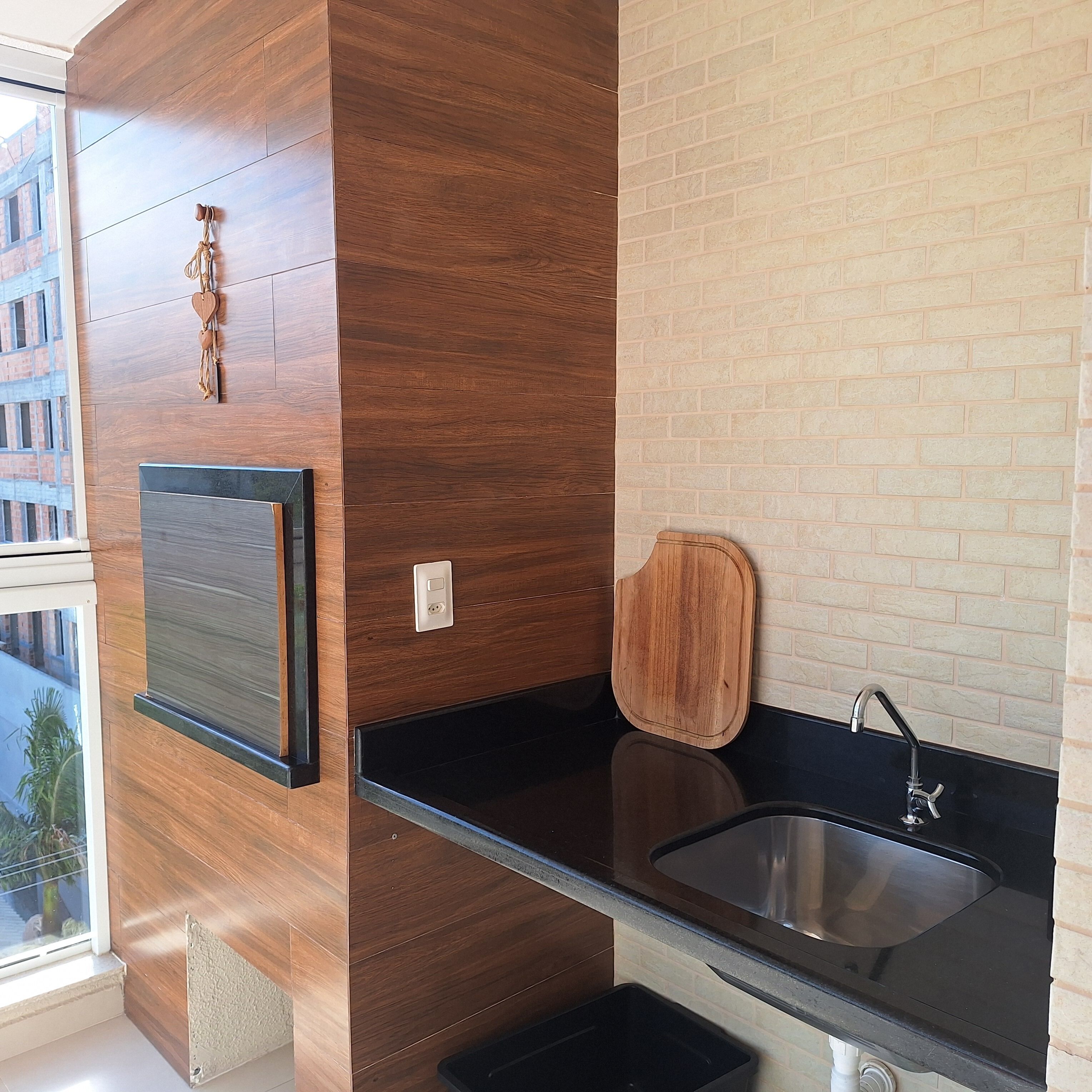 A modern kitchen with wooden cabinetry, a black countertop, and a stainless steel sink.