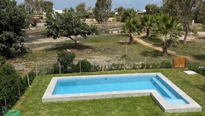 Una piscina rectangular con borde de hormigón, rodeada de un césped cuidado.