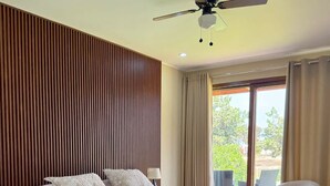 Un dormitorio moderno con una cama grande, un ventilador de techo y vistas al exterior.