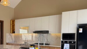 Una cocina moderna con encimera de mármol, taburetes de bar de madera, refrigerador negro y electrodomésticos integrados.