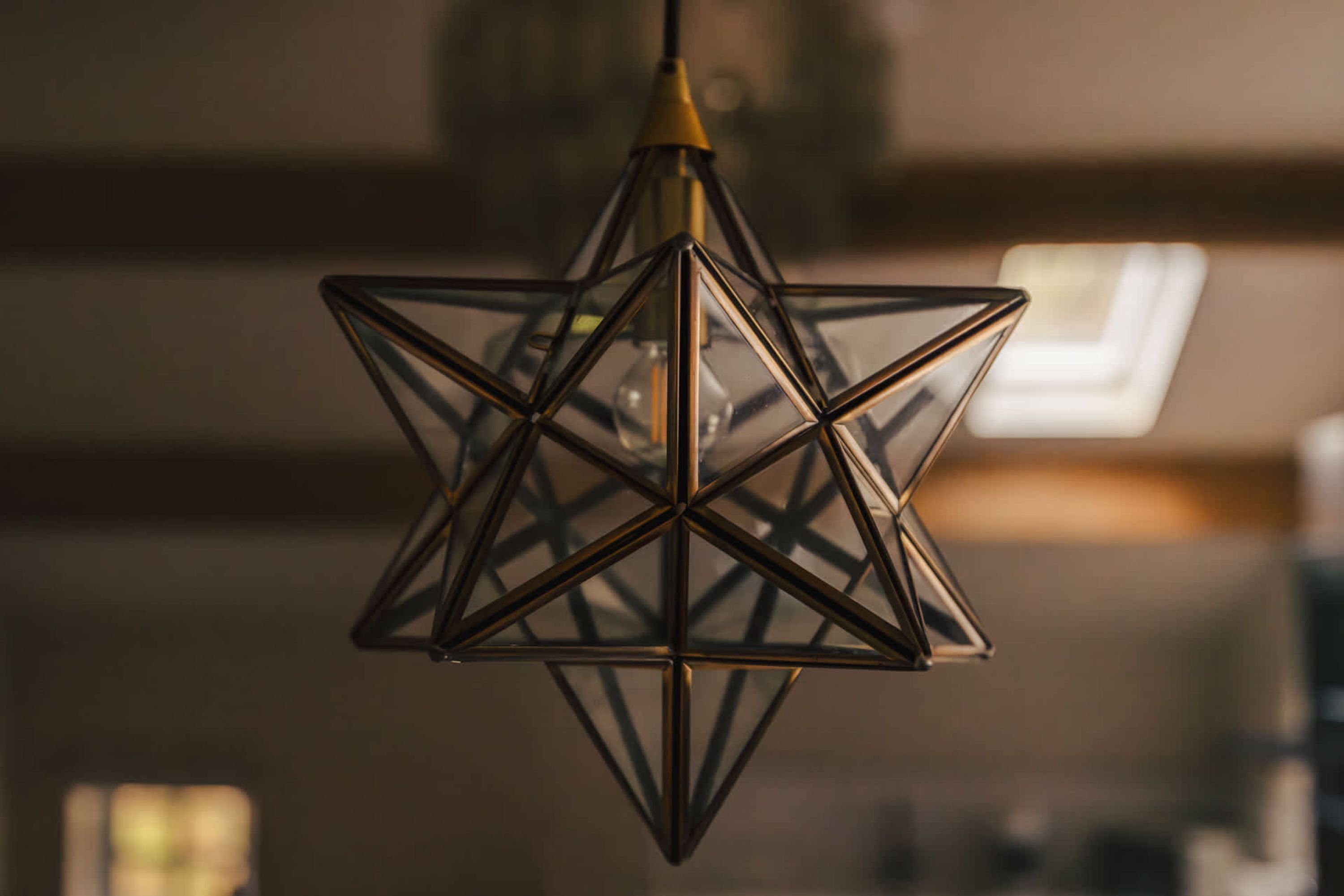 A geometric chandelier with a star-like design, hanging from a ceiling.