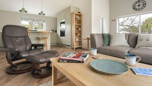 A modern living room with a brown leather chair, a wooden coffee table, a grey sofa, and a bookshelf. - The Lookout With 1 Bedrooms and 1 Bathrooms (Grange-over-Sands)