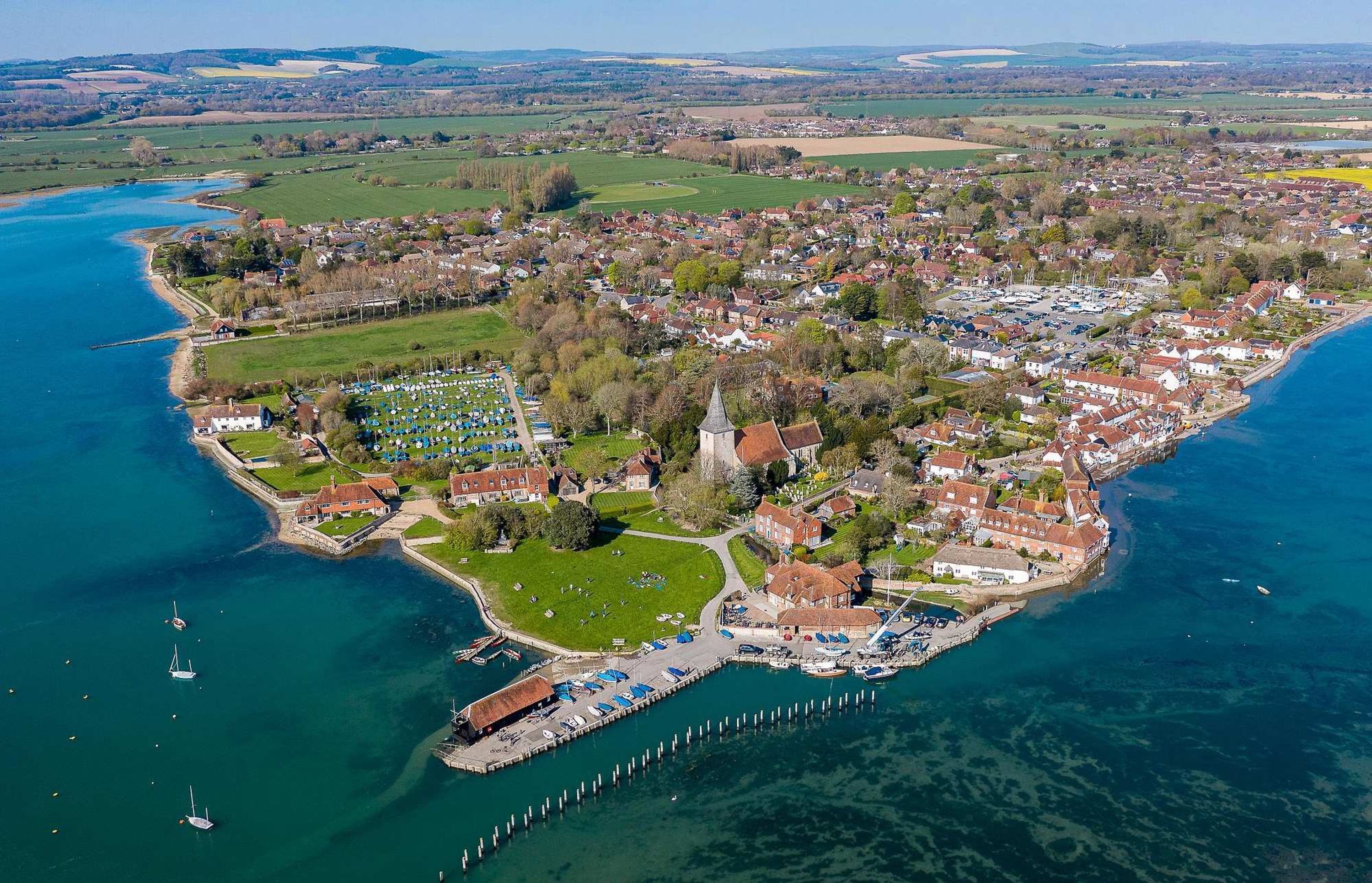 An aerial view of a coastal town with a marina, residential areas, and a prominent church.