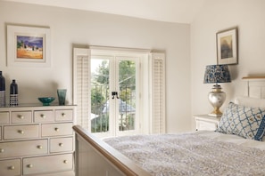 A bedroom with a bed, dresser, lamp, and two framed pictures. - Glen Bank in Brampton (Appleby-in-Westmorland)