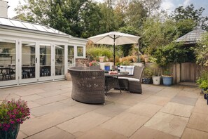 A patio with wicker furniture, a table, and an umbrella. - Glen Bank in Brampton (Appleby-in-Westmorland)