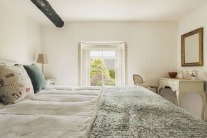 A bedroom with a bed, a desk, a chair, and a window with a view of greenery. - Glen Bank in Brampton (Appleby-in-Westmorland)