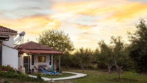 A house with a tiled roof, a covered porch, and a garden with a lawn and trees. - Petalidi Sunny Home One - Charming Garden Nest (Messini)
