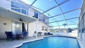 Una piscina interior con techo de vidrio, sillas azules y una mesa.