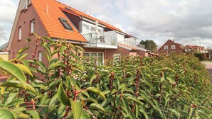 A red-brick house with a sloped roof and a balcony. - Exclusive vacation apartment in Norddeich, just a few minutes' walk from the sea. (Norden)