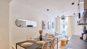A modern dining area with a long table, chairs, and a central vase. - Sublim Apartment Paris Center Beaubourg Le Marais (Paris)