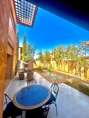 A patio with a pool, outdoor furniture, and a view of trees and a building. - Luxury escape: private villa 12 minutes from Jemaa el-Fna square (Marrakech)