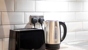 Ein Toaster und ein Wasserkocher stehen auf einer Küchenarbeitsplatte mit einer gefliesten Rückwand.