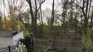 A backyard with a wooden fence, a small shed, and a garden area with plants and a stone border. - Forest’s Edge Elora | Private Yard, Fire Pit, Near Downtown (Salem)