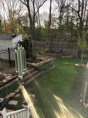 A backyard with a wooden fence, a small shed, and a garden area with plants and a stone border.