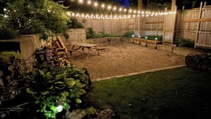 A backyard with a wooden deck, string lights, and a fire pit area. - Forest’s Edge Elora | Private Yard, Fire Pit, Near Downtown (Salem)