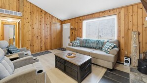 Una sala de estar acogedora con un sofá, una mesa de centro y una pared de madera.