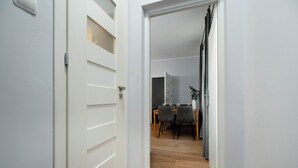 Un pasillo con una puerta blanca que da a un comedor con una mesa y sillas.