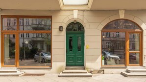 Un edificio con puerta verde, ventanas amplias y entrada con baldosas.