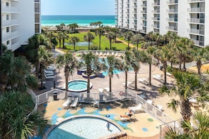 A resort with multiple swimming pools, palm trees, and a view of the ocean. - Mainsail 223 2 Bedroom Condo (Miramar Beach)