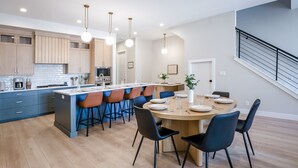 A modern kitchen with a central island, bar stools, and a dining area with a round table. - Weekend Vibes 5 Bedroom Townhouse (St. George)