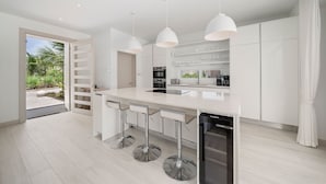 Une cuisine moderne avec des meubles blancs, des appareils en acier inoxydable et un îlot central doté de tabourets de bar.