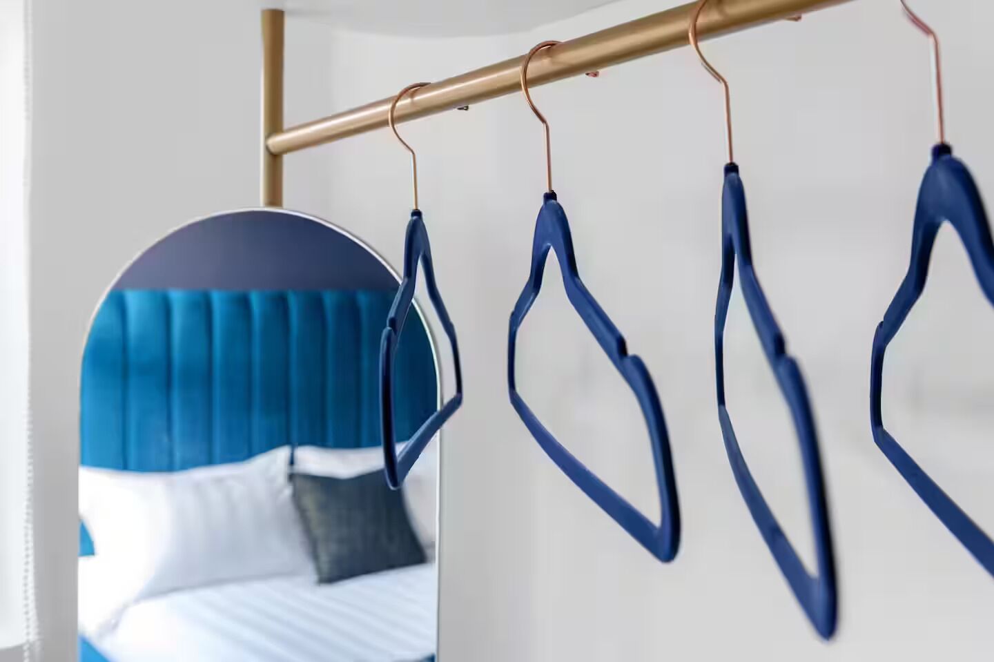 Une chambre à coucher avec un lit, une tête de lit bleue et un miroir qui reflète la pièce.