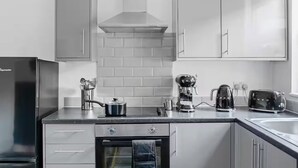 A modern kitchen with stainless steel appliances, white cabinetry, and a tiled backsplash. - The Navy Nest Luxury Home Nottingham City Centre (Nottingham)