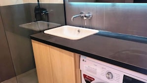 Un baño moderno con tocador de mármol, lavamanos y lavadora.