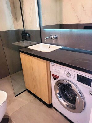 A modern bathroom with a marble vanity, a sink, and a washing machine. - Axis Towers Executive 1BR with City Views 28+ Night Stays (T'bilisi)