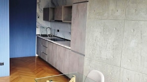 Una cocina moderna con salpicadero de mármol, armarios de madera y una mesa de comedor de vidrio con sillas.