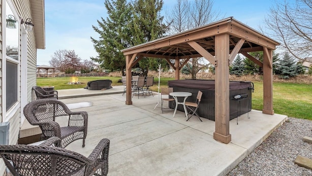 A covered outdoor patio with a grill, seating, and a pergola structure. - Atlas Farm Stay Retreat Patio/Hot Tub (Coeurdalene)