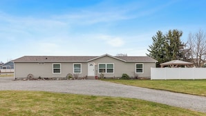 A single-story house with a front porch, a garage, and a fenced yard. - Atlas Farm Stay Retreat Patio/Hot Tub (Coeurdalene)