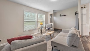 A living room with two sofas, a coffee table, a lamp, and a TV. - Atlas Farm Stay Retreat Patio/Hot Tub (Coeurdalene)
