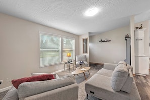Ein Wohnzimmer mit zwei Sofas, einem Couchtisch, einer Lampe und einem Fernseher.