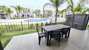 Ein Poolbereich mit Tisch und Stühlen, einem Schwimmbecken und modernen Gebäuden im Hintergrund.