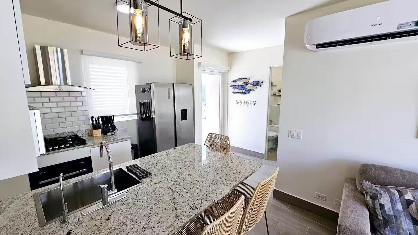 Una cocina moderna con encimeras de granito, electrodomésticos de acero inoxidable y una isla central con asientos.
