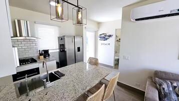 Una cocina moderna con encimeras de granito, electrodomésticos de acero inoxidable y una isla central con asientos.