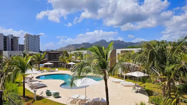 Ein Resort mit Swimmingpool, Liegestühlen und Palmen.