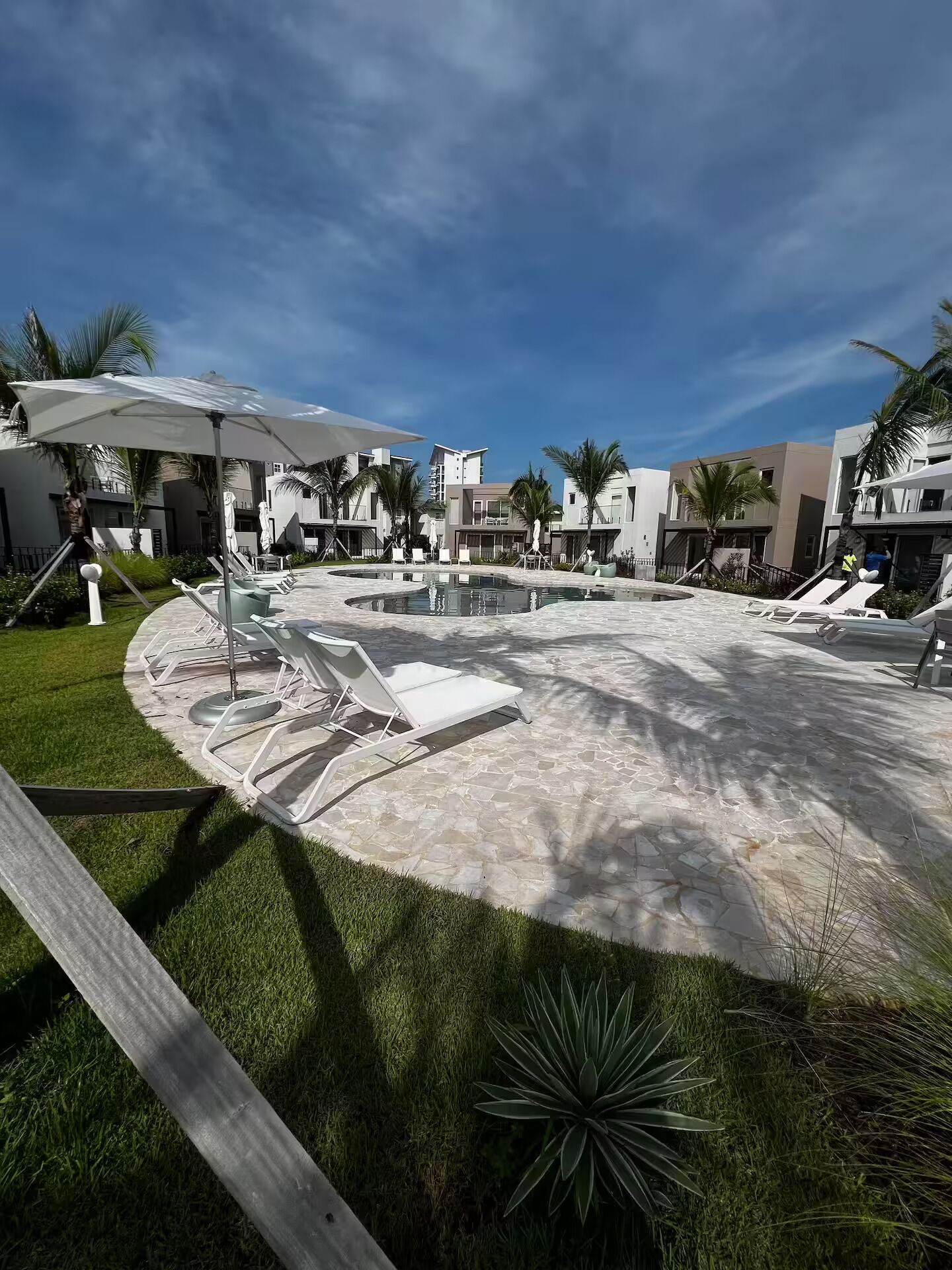 Um resort moderno com área de piscina, espreguiçadeiras e palmeiras.