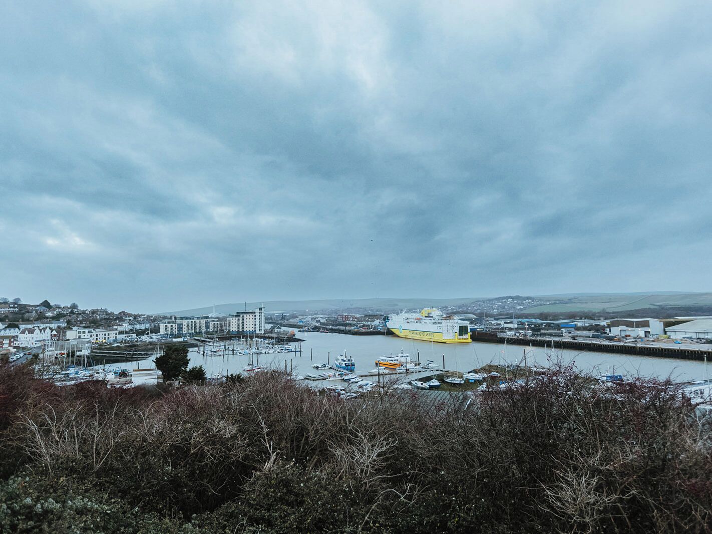 A harbor with a large ship docked, surrounded by buildings and boats.