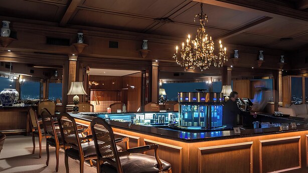 Eine luxuriöse Bar mit einer Theke, Sitzmöglichkeiten und einem großen Kronleuchter.
