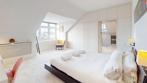 Une chambre d’hôtel moderne équipée d’un grand lit, d’une chaise, d’un bureau et d’une armoire.