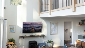 A spacious living room with a large flat-screen TV, a wooden staircase, and a cozy seating area. - Modern Chalet with Spa Bathoom (Seward)