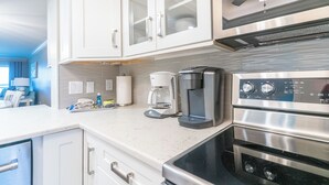 Eine Küche mit weißen Schränken, einer Kaffeemaschine, einem Toaster und einem Herd.