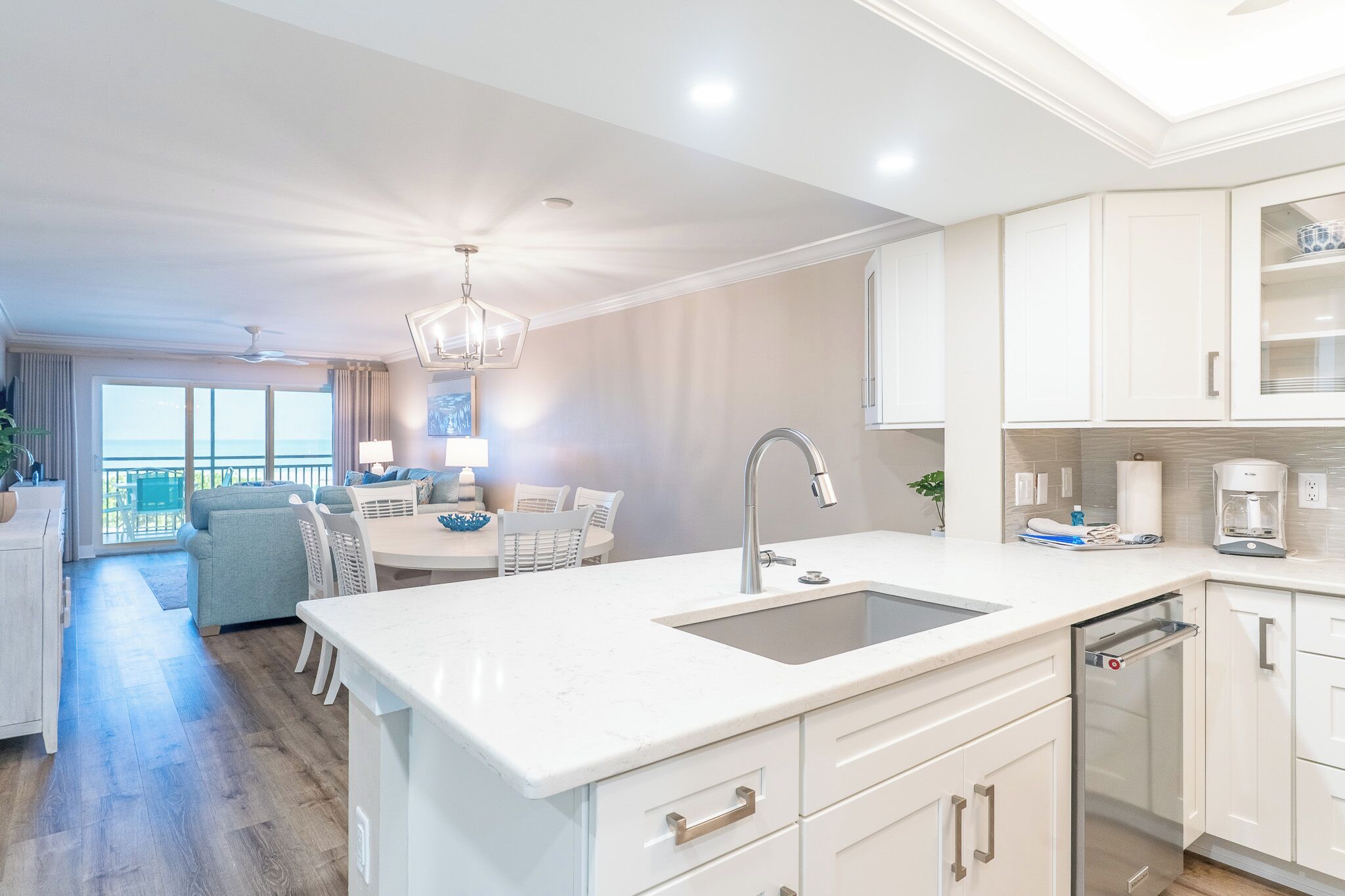A modern kitchen with a central island, white cabinetry, and a large window overlooking a balcony.