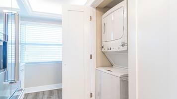 A laundry room with a washing machine, a dryer, and a glass door leading to a balcony.