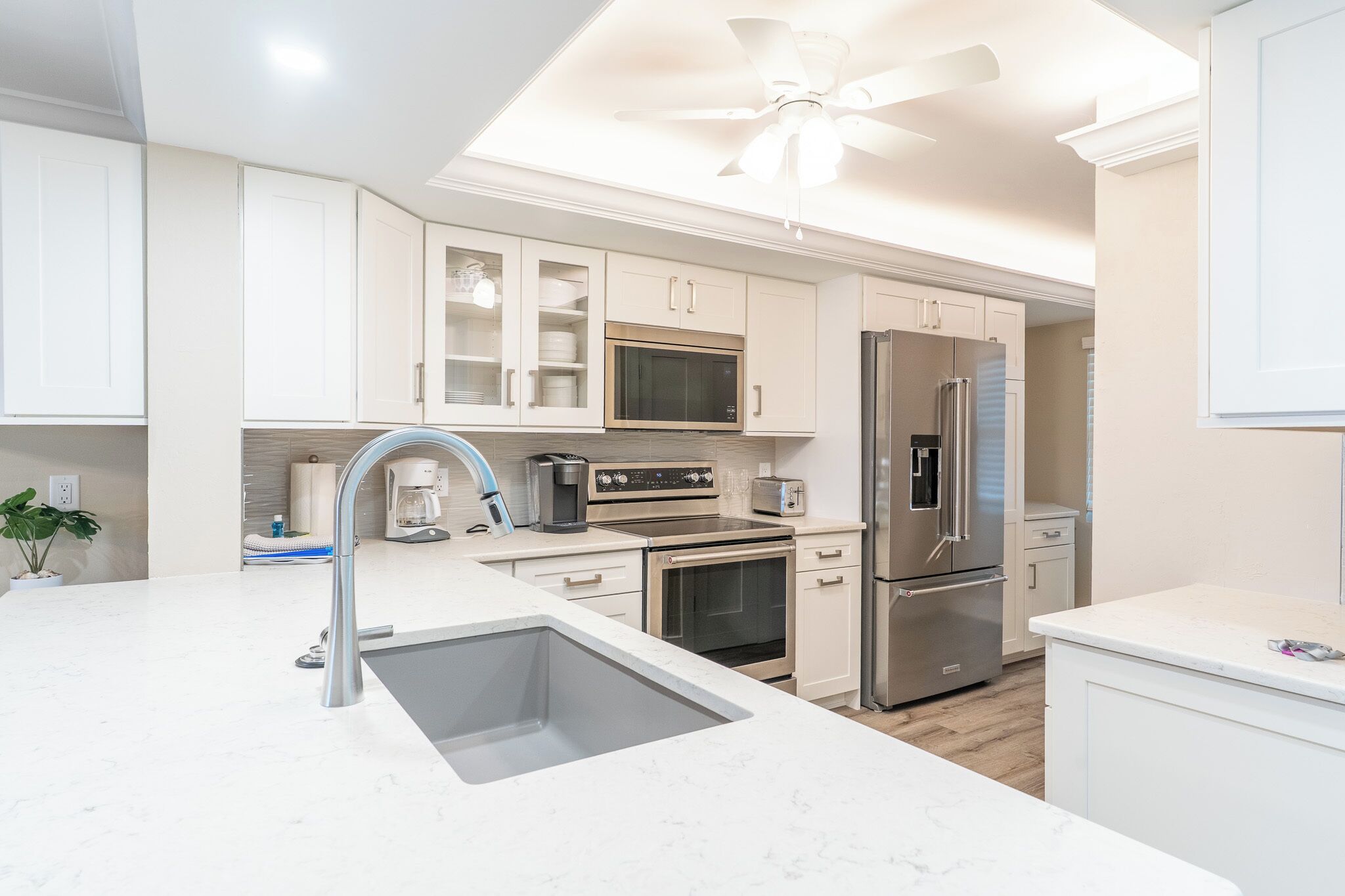 A modern kitchen with white cabinetry, stainless steel appliances, and a central island with a sink.